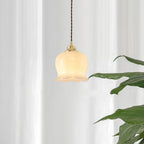 Brass petal pendant light glowing warmly beside a wall