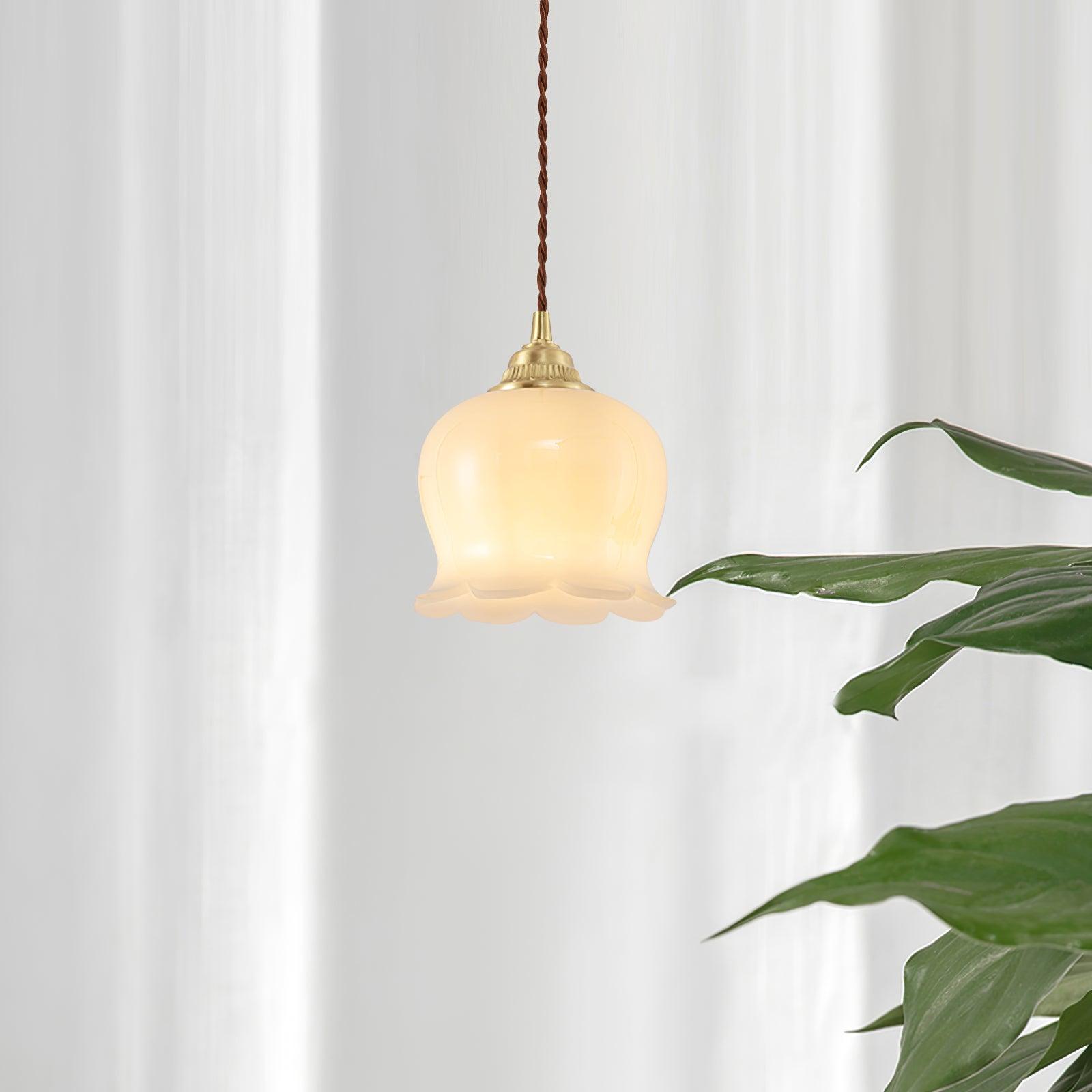 Brass petal pendant light glowing warmly beside a wall