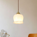 Flower pendant light in brass and white against a neutral wall