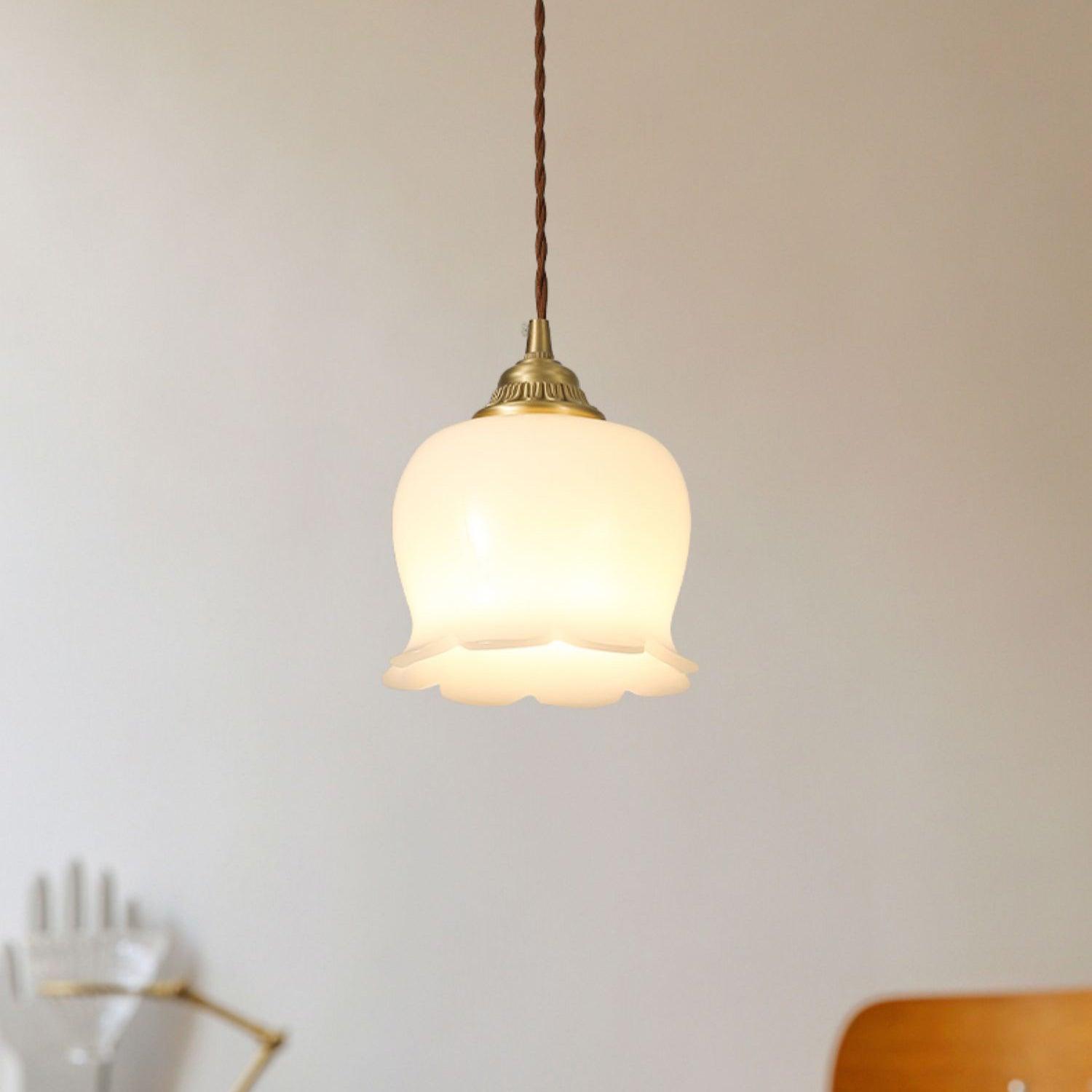Flower pendant light in brass and white against a neutral wall