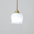 Brass pendant light with white petal shade glowing in a soft interior