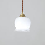 Brass pendant light with white petal shade glowing in a soft interior
