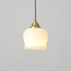Petal-shaped pendant light in brass and white suspended from a cord