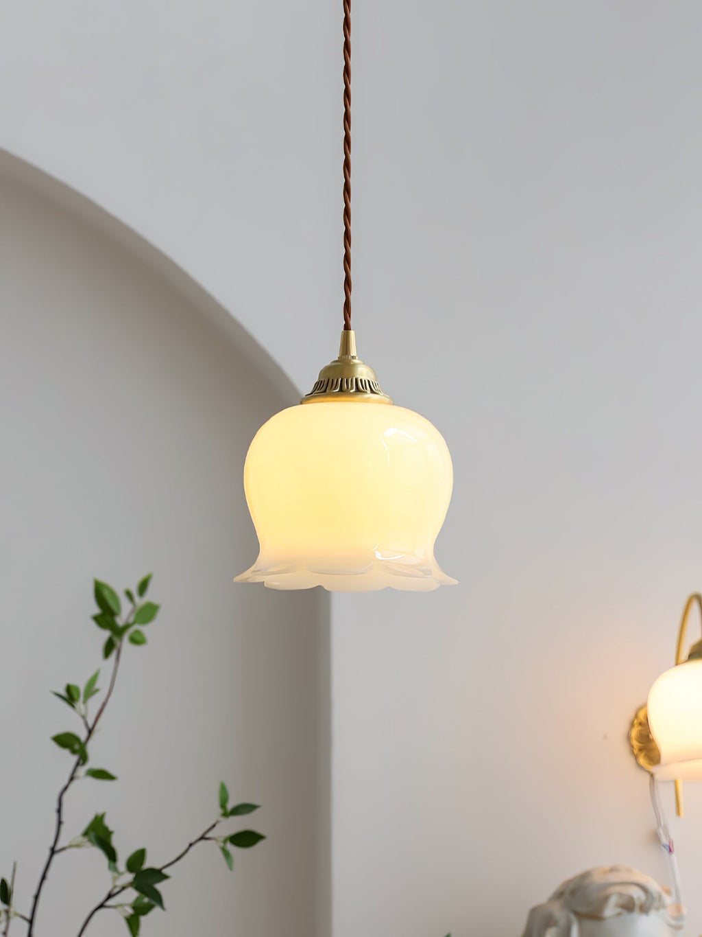 Swag pendant light with brass and petal shade against a pale wall
