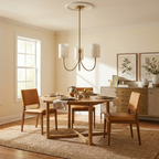 Set over a round dining table beside a wood sideboard, this Clérachic chandelier hangs in a brass finish.