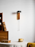 Angled toward the room, this Clérachic wall light is mounted above a table set with a book and teacup.