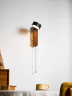 Facing straight out from the wall, this Clérachic wall light hangs beside a bookcase of cups and books.