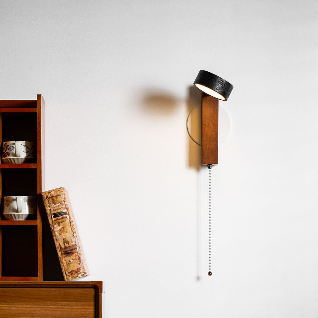 Turned away, this Clérachic wall light shows mostly its walnut arm against the cream wall.