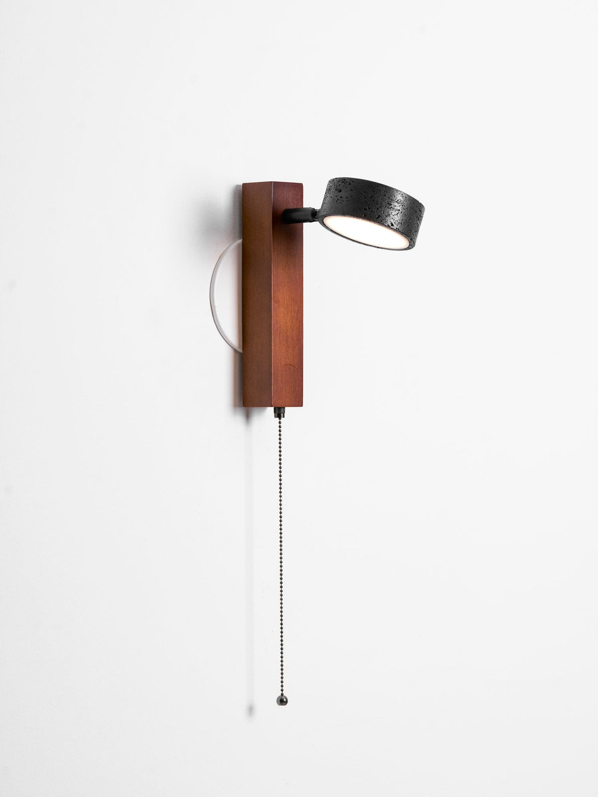 On white, this Clérachic wall light faces forward with its pull chain hanging from the walnut base.