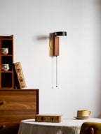 Turned nearly out of view against a cream wall, this Clérachic wall light hangs near a bookcase of cups and books.