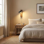 A mug and pull chain sit on the bedside table beneath this Clérachic wall light, in a linen-toned bedroom.