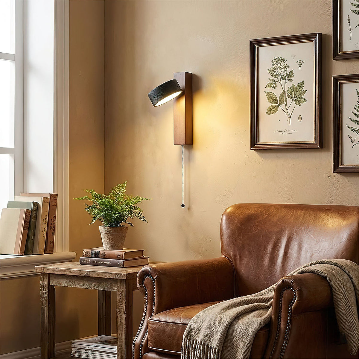 A leather armchair, framed botanical prints and a side table of books sit beneath this Clérachic wall light.