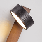Extreme close view of the black travertine drum shade on this Clérachic wall light, its stone-like texture visible.