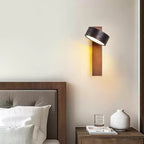Beside a dark wood bed frame with a candle and small vase on the nightstand, this Clérachic wall light glows warm.