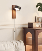 Beside a wood cabinet holding a vintage radio, this Clérachic wall light glows warm with its pull chain hanging down.