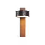 Front view of this Clérachic wall light on white, warm light glowing inside its black travertine drum shade.