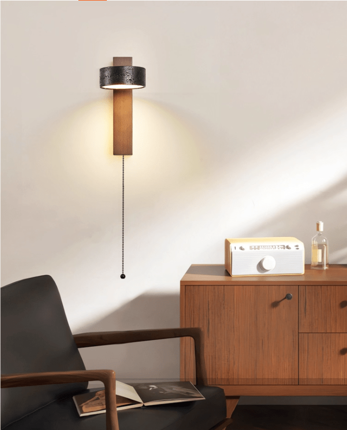Sunlight rakes across the wall behind this Clérachic wall light, glowing beside a cabinet with a radio and bottle.