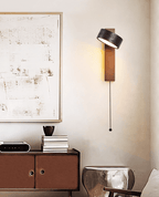 An abstract painting and a sideboard with books and a small sculpture sit beneath this Clérachic wall light.