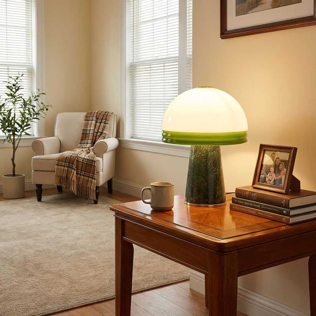 This Clérachic table lamp glows on a side table beside a cream armchair draped with a plaid throw, under a window.