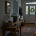 Lit on a console table in a dim entryway, this Clérachic table lamp sits near a woven basket by the front door.