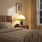 On a walnut nightstand, this Clérachic dome lamp glows beside a bedside clock and a stack of books at dusk.