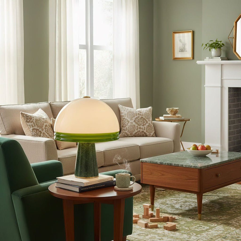 Clérachic dome table lamp lit on a round side table in a living room with a green sofa and a white fireplace mantel.