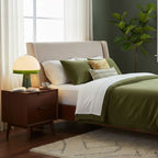 Beside a bed dressed in green and cream linens, the Clérachic dome table lamp glows on the bedside table.