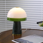A Clérachic dome lamp lit on the round table, its cord visible beside a magazine on the lower shelf.
