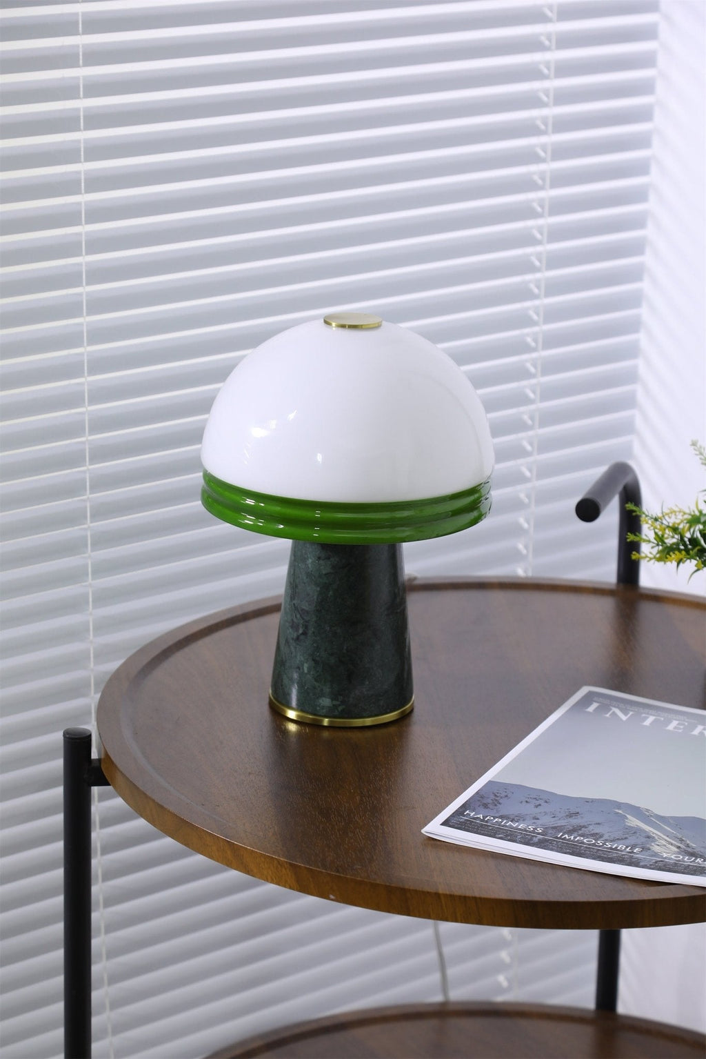 The Clérachic table lamp lights the round table, its two-tier stand and a magazine visible below.