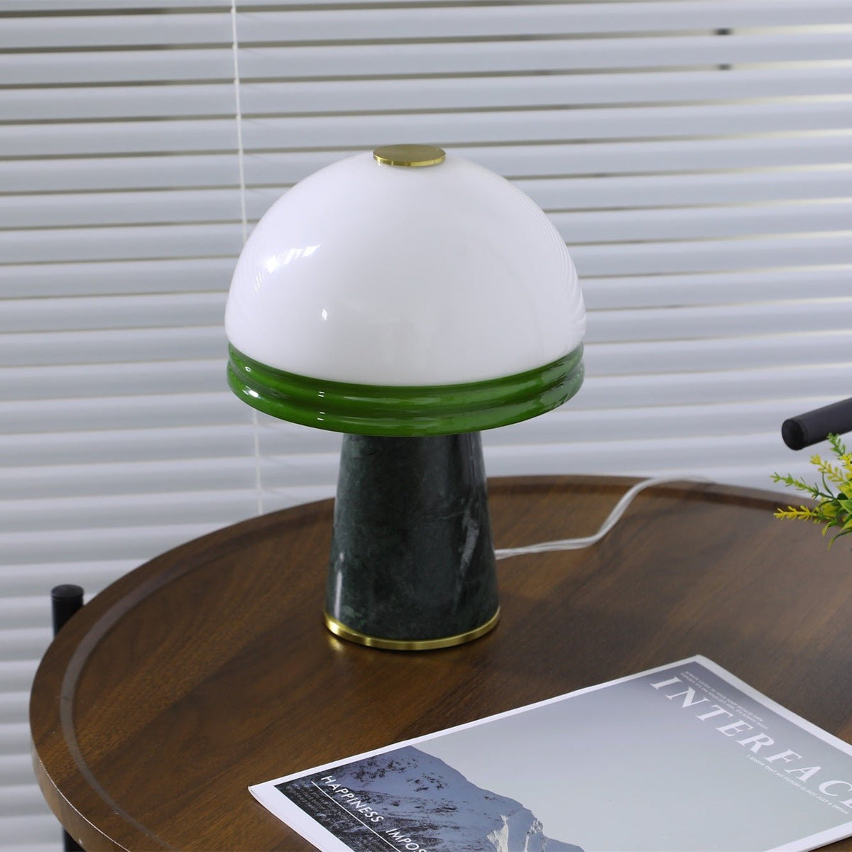 An angled shot of the lit Clérachic table lamp, its brass base catching a reflection on the tabletop.