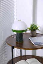 A narrow crop shows the Clérachic dome lamp above a lower shelf holding an open book on the round table.