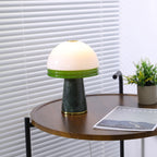 A closer crop of the Clérachic dome lamp lit on the round table, the green glass rim catching the light.