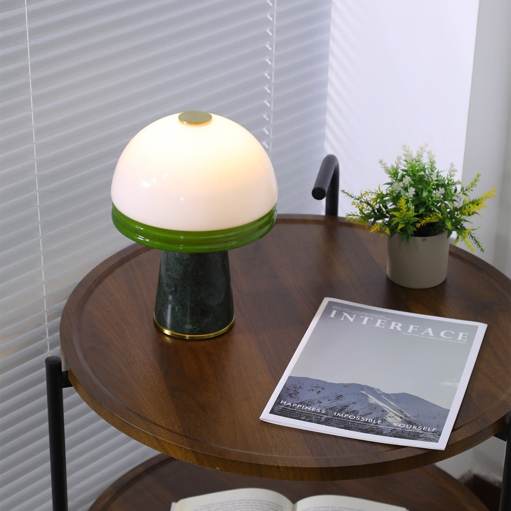 Seen from a lower angle, the Clérachic dome lamp lights the round table above a shelf stacked with books.