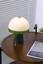 A close, cropped view of the Clérachic table lamp's white dome and green rim on the round tabletop.