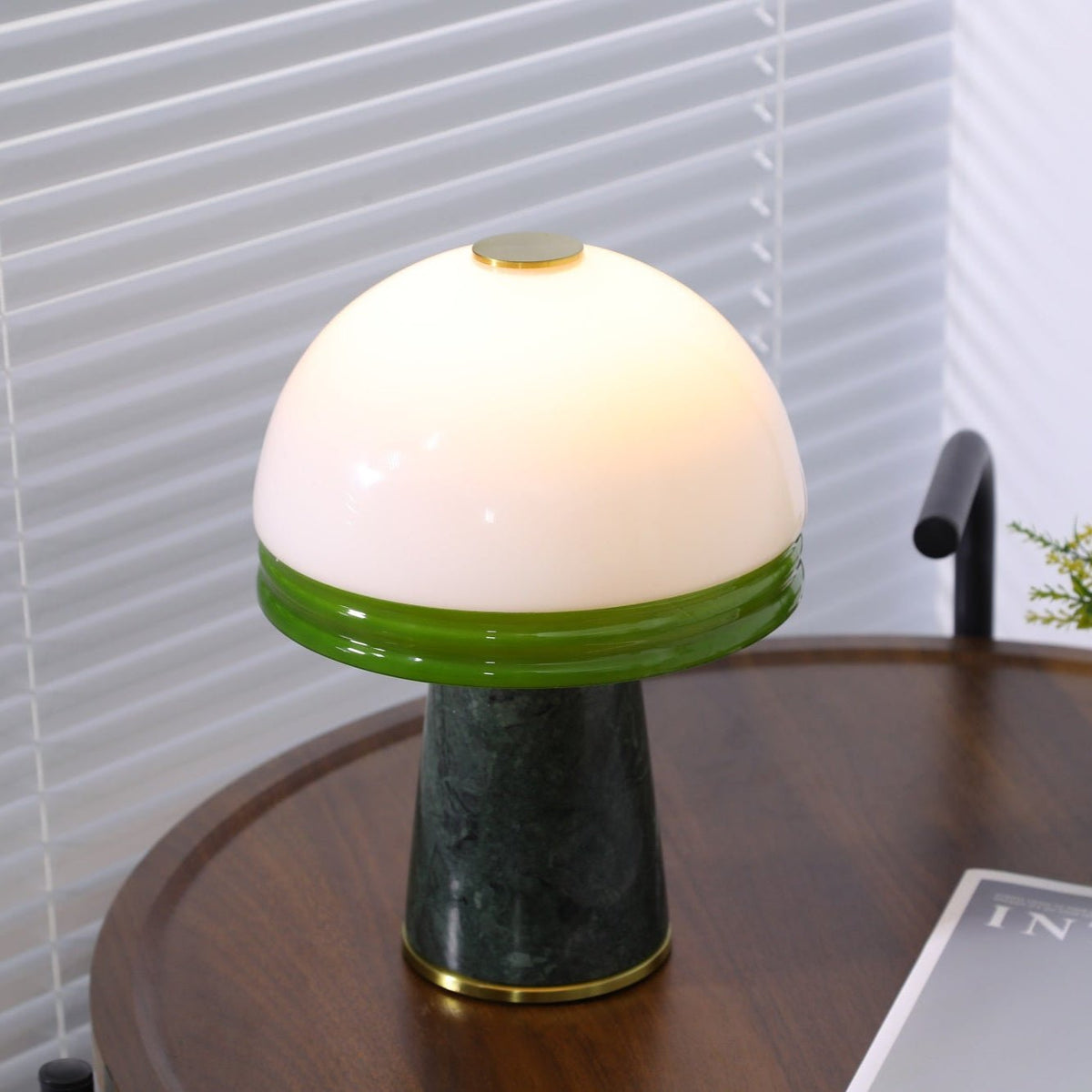 Extreme close-up on the Clérachic dome lamp's brass finial button atop the lit white glass shade.
