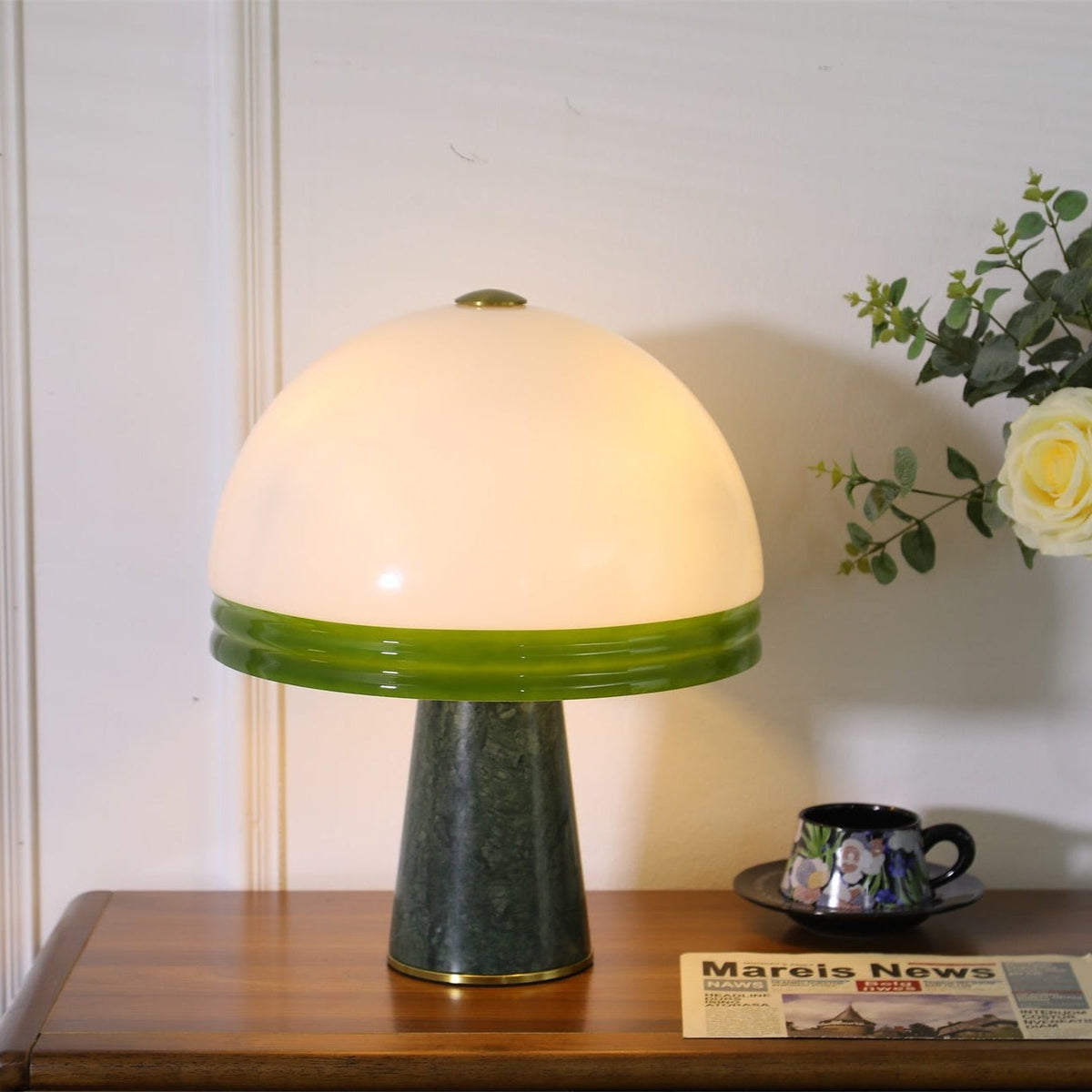 Straight-on close-up of the lit Clérachic dome table lamp on a cabinet, its cord trailing down beside the base.