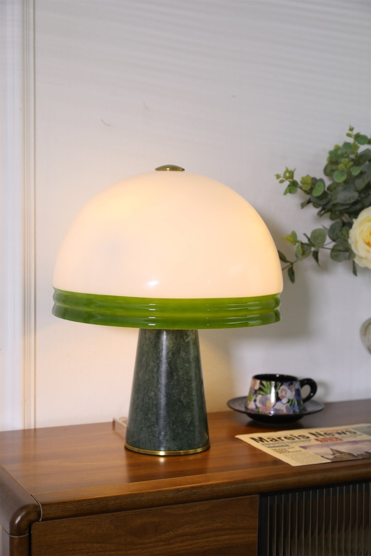 Tight crop of the lit Clérachic dome table lamp showing mostly the shade and upper base, cord visible at its foot.