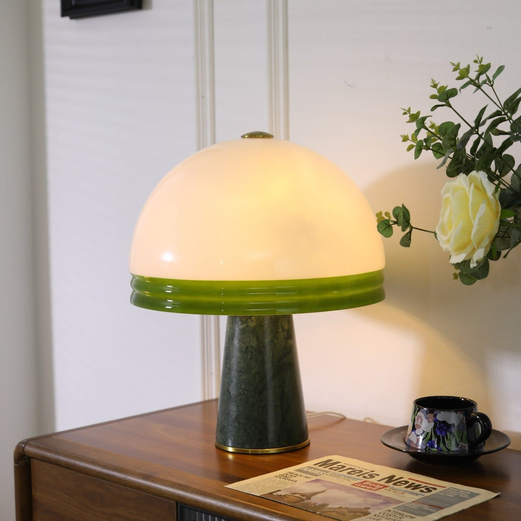 A patterned coffee cup, folded newspaper and single rose share the wood dresser with the lit Clérachic dome table lamp.