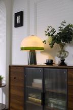 A black-framed picture hangs above the sideboard where the Clérachic dome table lamp glows beside a rose in a glass vase.
