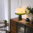 Beside a window with blinds, the Clérachic dome table lamp lights a wood sideboard next to a small round table holding a laptop.