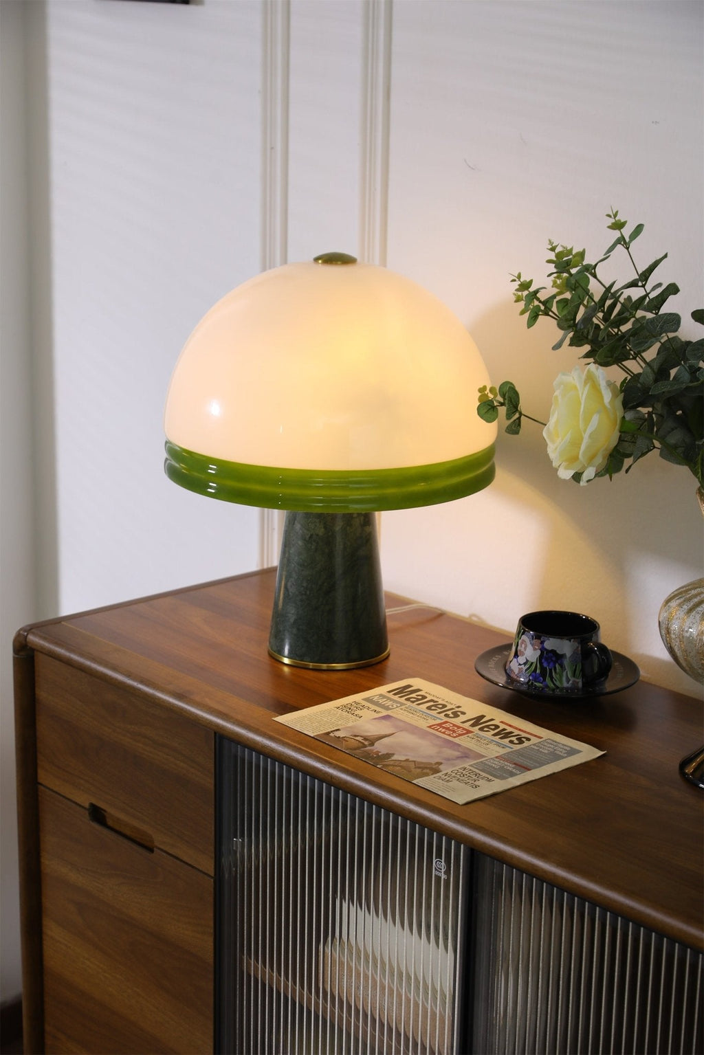 Clérachic dome table lamp lit in a tight crop against a plain panelled wall, with no window visible in this frame.