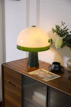 Clérachic dome table lamp lit in a tight crop against a plain panelled wall, with no window visible in this frame.