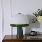 Clérachic dome table lamp shown unlit on a cabinet, its green marble base clearly visible beside a teacup and rose.