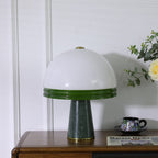 Seen from a standard three-quarter view, the unlit Clérachic dome table lamp sits on the wood cabinet beside a teacup.