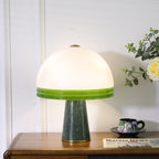 Its green marble base and brass foot ring in full view, the unlit Clérachic dome table lamp sits on the wood cabinet.