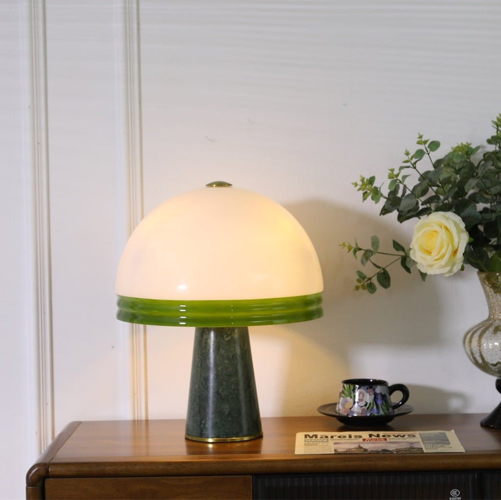 Close crop of the lit Clérachic dome table lamp's ribbed green shade band, with a cream rose in the background.