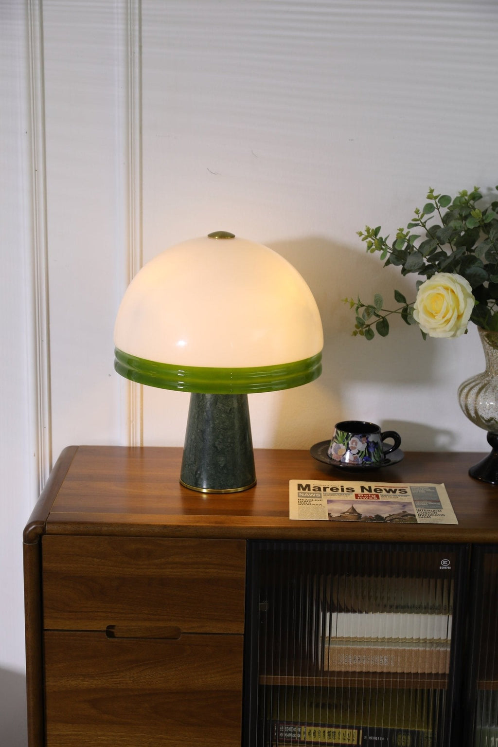 Clérachic dome table lamp lit beside a clear glass vase of white flowers, with no newspaper in this crop.