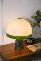 Tighter crop of the lit Clérachic dome table lamp on a cabinet, its power cord visible trailing to the right.