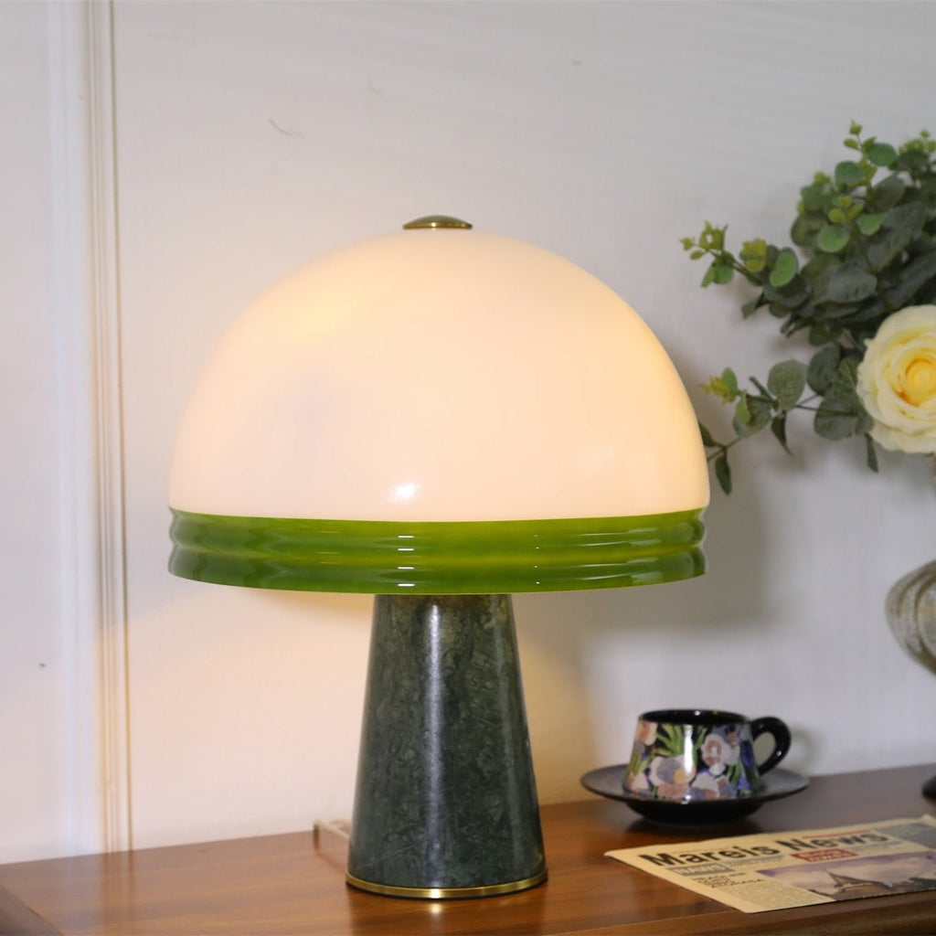 A small cream rose sits in the background as the Clérachic dome table lamp glows on a wood cabinet beside the shade.