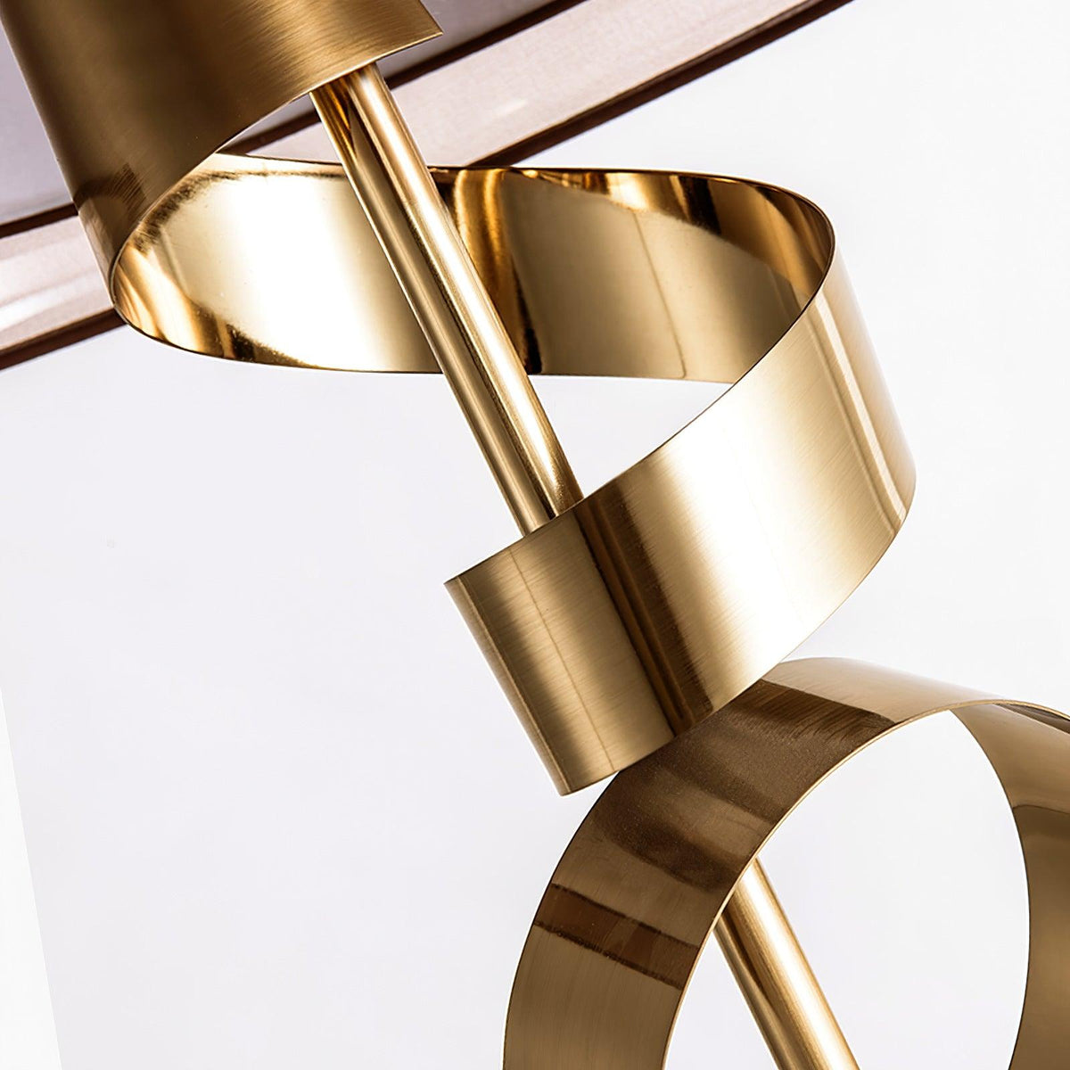 Macro detail of the Clérachic lamp's gold ribbon spiral shown alone against a white background, its curves fully exposed.